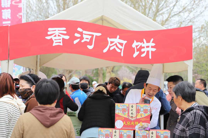 游客在“香河肉饼”展位前了解肉饼制作过程。张涵摄