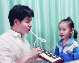 杨俊鑫向学生展示口风琴的演奏方法。