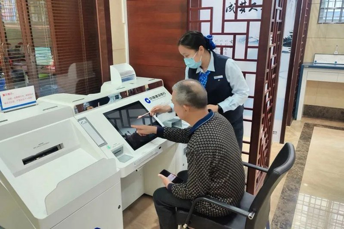 图为建设银行厦门市分行工作人员指导老年客户使用智慧柜员机。 郝云丽 摄