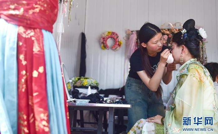   4月14日，在洛阳市中国国花园一家汉服体验馆里，游客在体验汉服妆造。
