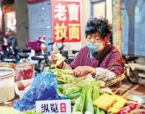     4月10日，“炸串奶奶”贾美兰正在为顾客炸串。 纵览新闻见习记者 常曌宇摄