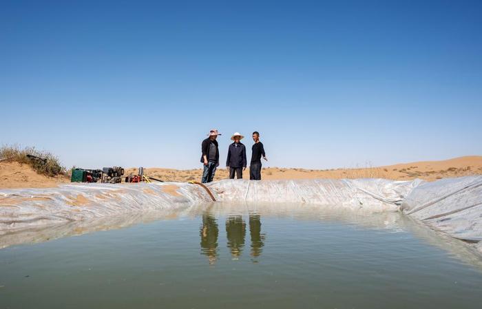   4月10日，在古浪县八步沙林场麻黄塘沙区，八步沙第二代治沙人郭万刚（中）和郭玺（右）查看沙漠里的蓄水池。
