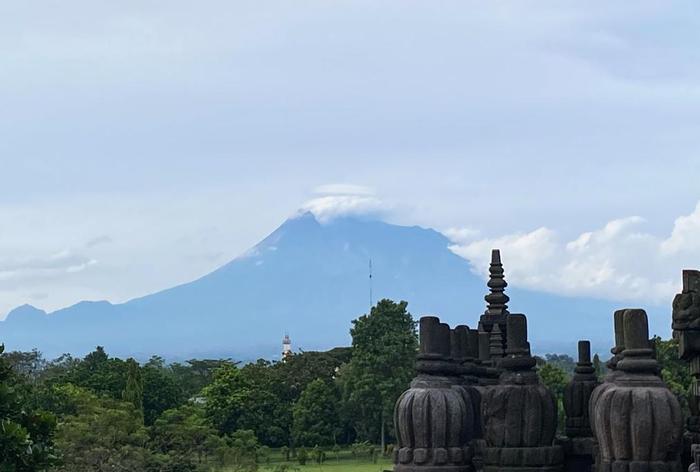 图为2023年2月4日在印度尼西亚日惹特区拍摄的巴兰班南神庙一角和远处的默拉皮火山。新华社记者徐钦摄