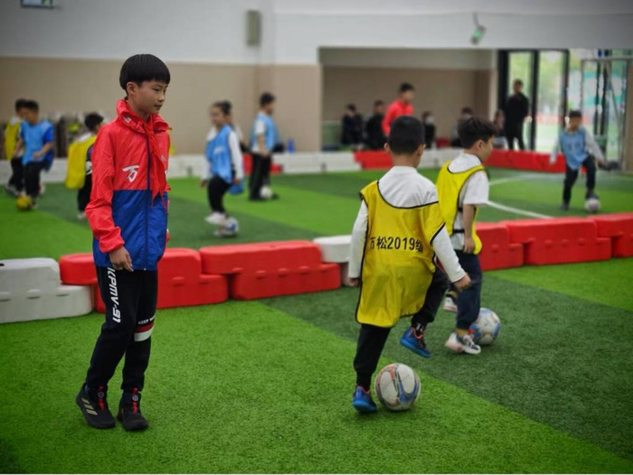万松园路小学学生助教（左一）指导学生上足球课。（万松园路小学供图）