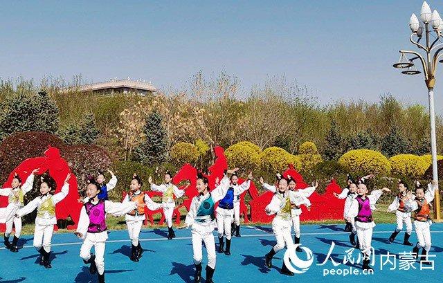 内蒙古小鸿雁艺术团的孩子们正在花丛旁翩翩起舞。人民网记者 富丽娟摄