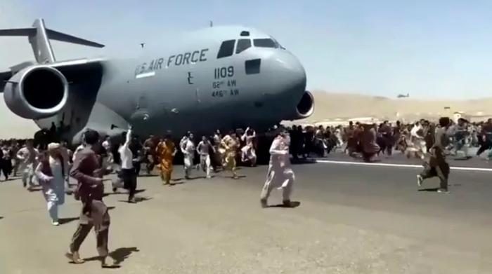 2021年8月16日，一架美军C-17运输机沿着喀布尔机场跑道滑行，人们在旁边奔跑。视频截图