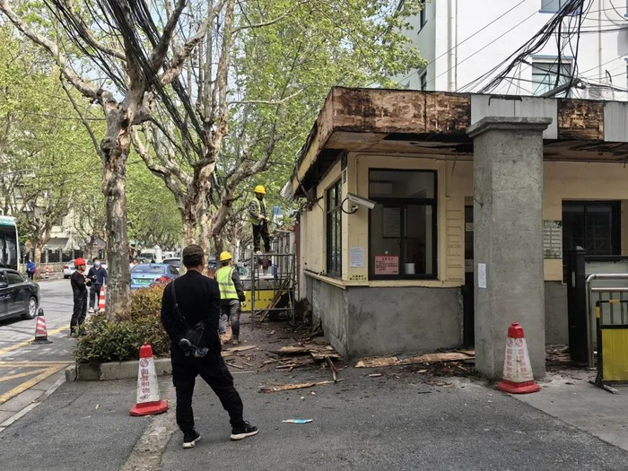 △但东侧人行道也不好走。图为施工人员正在清理铲除沿线小区的外墙墙皮，更新小区的门头。