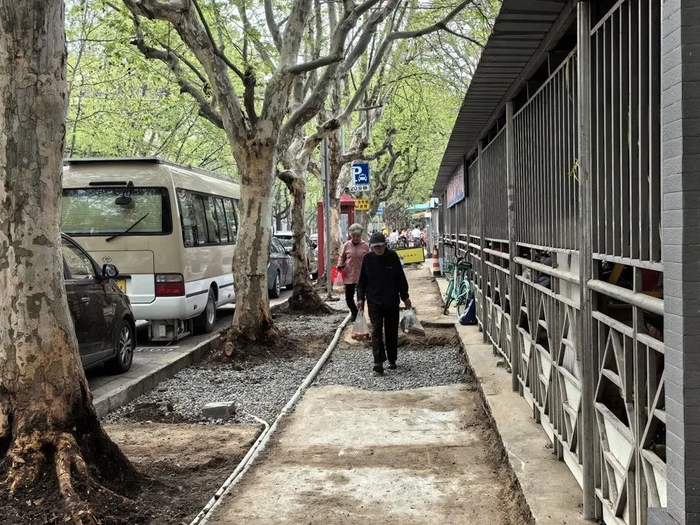 △频繁开挖给附近居民带来了不少困扰。图为一些老人仍选择在施工区域行走，一路拎着刚买的菜，埋着头谨慎地选择下脚处。