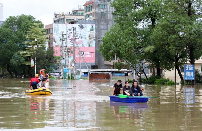 4月21日，广东清远英德市浛洸镇居民在积水的道路上乘船出行。新华社记者 黄国保 摄
