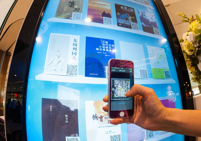 2014年7月22日，一名重庆市民用手机扫描商场内的电子借阅机上的二维码来下载图书。