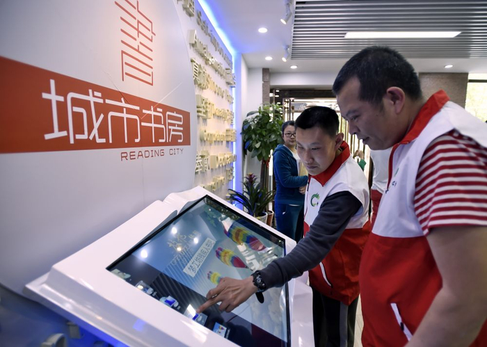 2016年4月21日，居住在北京市朝阳区左家庄的两位残疾人在城市书房使用残疾人专用的电子阅读器查找资料。
