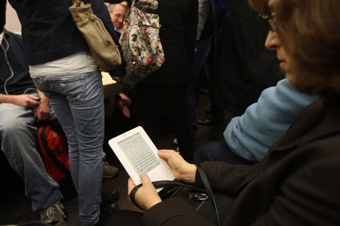 2010年3月17日，在美国纽约的地铁车厢里，一名乘客（右）在用亚马逊网上书店的Kindle电子阅读器读书。