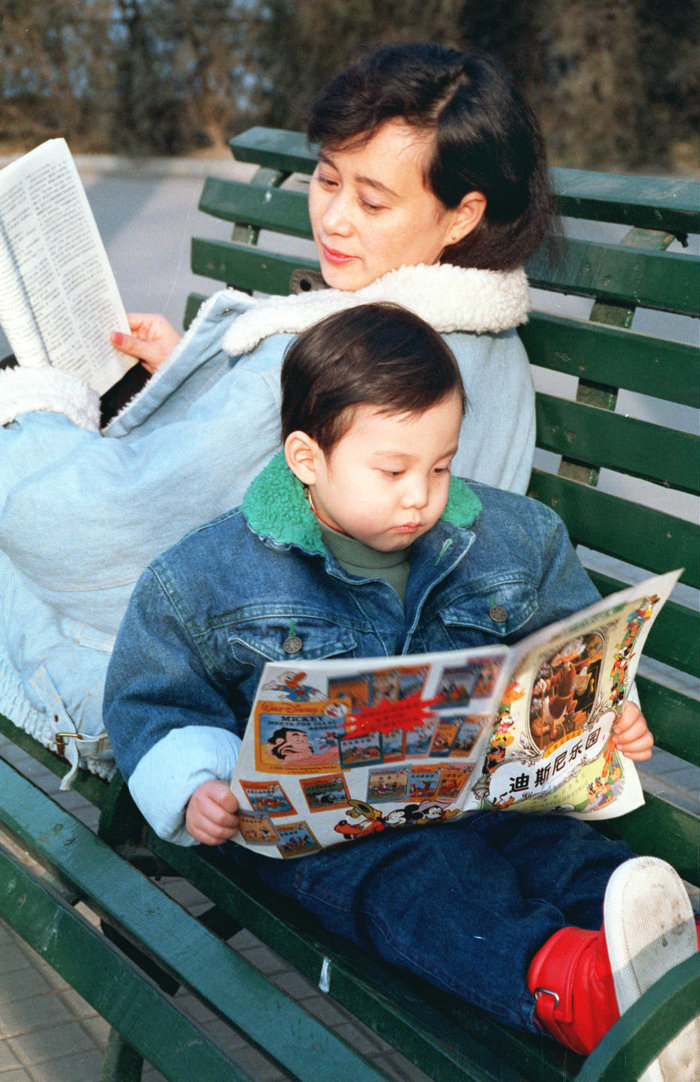 1990年，一位年轻妈妈和她的儿子在公园休憩，阅读。