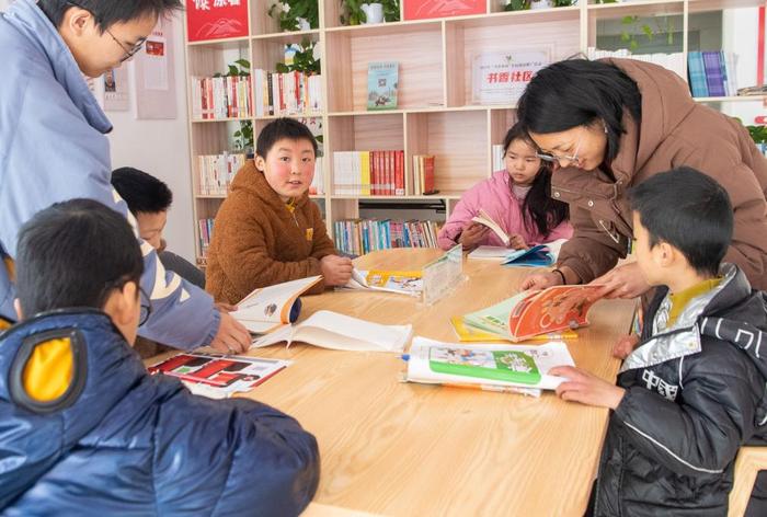   1月24日，在重庆市巫山县骡坪镇路口村数字农家书屋内，“临时家长”和孩子们一起阅读书籍。新华社记者 唐奕 摄