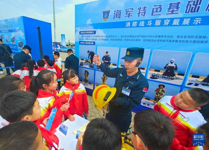   海军唐山舰靠泊河北省唐山市开放展示，官兵为小学生演示消防战斗服穿戴（4月20日摄）。新华社发（马玉彬 摄）