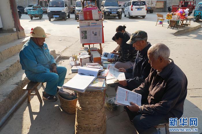 村民围在书摊前看书（4月7日摄）。新华网 范芳钰 摄