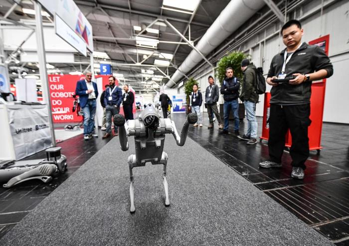 4月22日，在德国汉诺威工博会上，杭州宇树科技有限公司参展商（右一）在展示一款机器狗。新华社记者任鹏飞摄