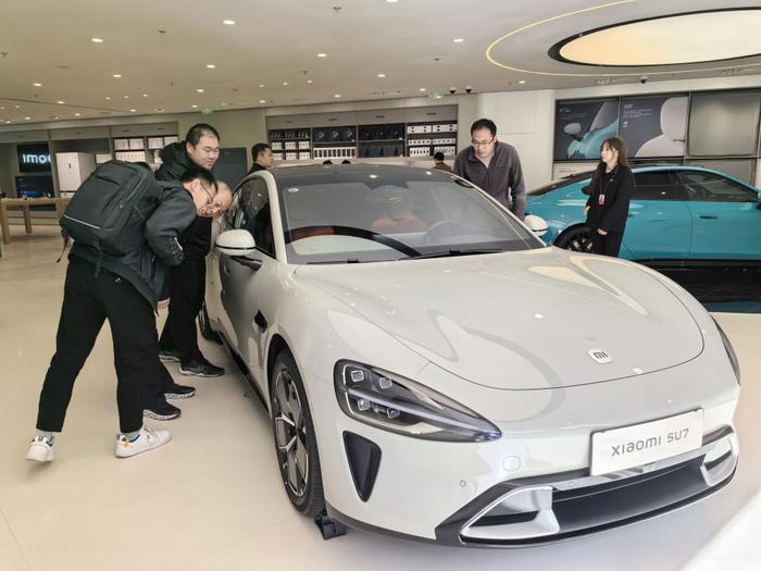 ↑ 在北京一家小米汽车零售门店内，消费者在了解小米新能源汽车SU7（3月28日摄）。新华社记者 鞠焕宗 摄