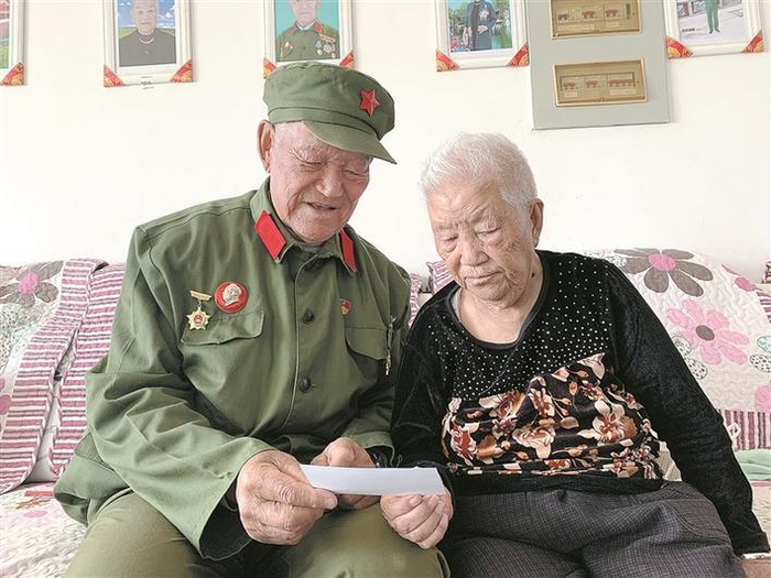     老军垦马福元（左）和妻子在翻看以前的照片（资料图片）。谢增杰  摄