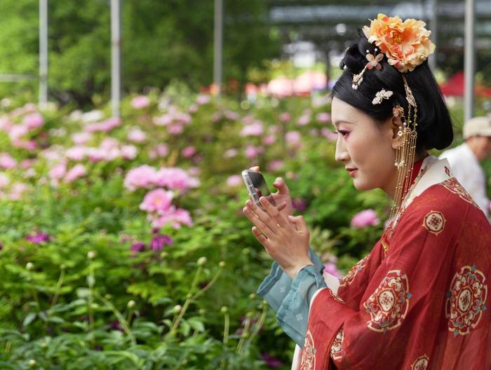 4月16日，身着传统服饰的游客在河南省洛阳市中国国花园赏花拍照。新华社记者 李嘉南 摄