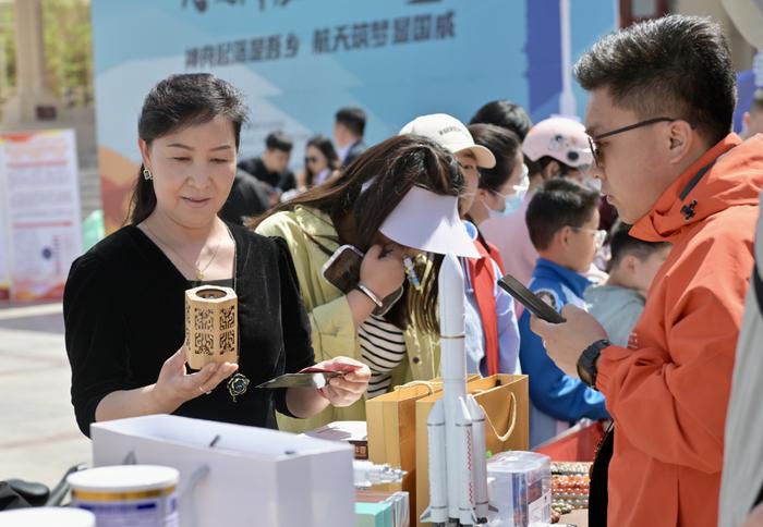 4月26日，人们在东风航天城东风礼堂前组织的主题活动上选购文创产品。