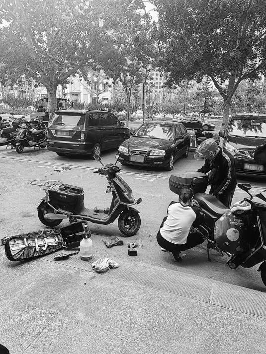 褡裢坡附近一门店人员正在修车，电动车电池仓被打开。