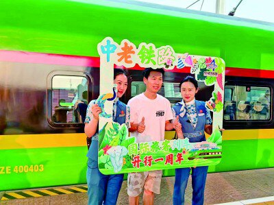 旅客与列车员庆祝中老铁路国际旅客列车开行一周年。张勇摄/光明图片