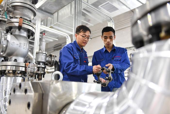 4月29日，在吉林化纤集团碳纤维原丝生产车间，毛炳淇（左）与同事曹泽民查看设备零部件。