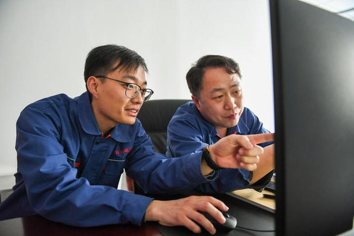 4月30日，毛炳淇（左）与同事郝东文研究改进生产工艺。