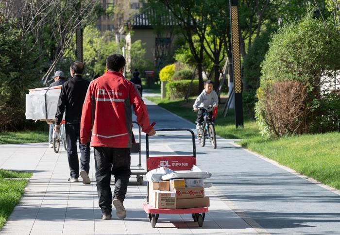 　　京东快递工作人员在住宅区内配送快递。