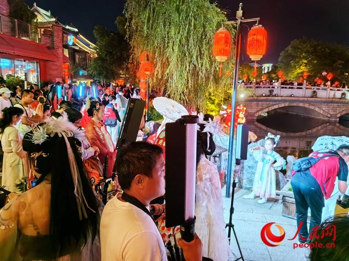 夜晚的洛邑古城迎来一天中的高光时刻，穿汉服打卡的游客排起了长队。人民网记者王佩摄