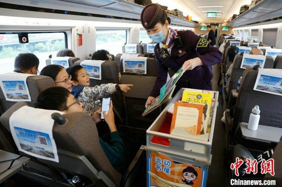 封盛给孩子介绍“流动书屋”内的书籍。中新网记者 殷立勤 摄