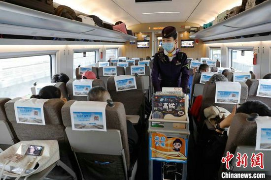 封盛推着“流动书屋”行走在列车车厢内。中新网记者 殷立勤 摄