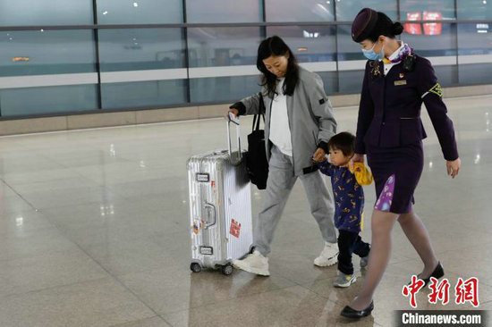 封盛帮助家长一起牵着孩子行走在站台上。中新网记者 殷立勤 摄