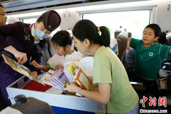 封盛给孩子介绍“流动书屋”内的书籍。中新网记者 殷立勤 摄