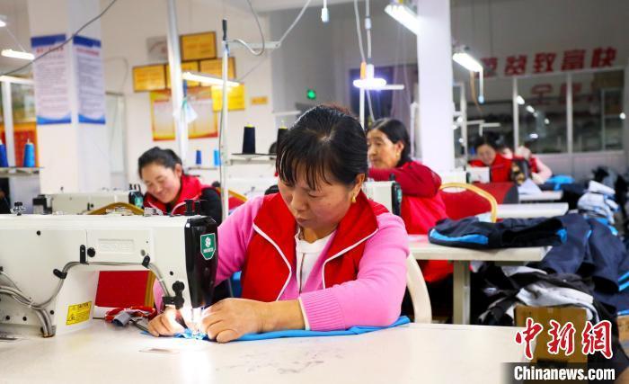 图为社区居民在制衣工厂工作。(资料图)艾庆龙 摄