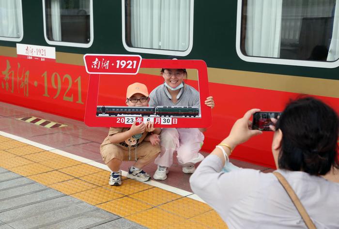   2023年6月30日，旅客在上海至嘉兴的Y701次“南湖·1921”红色旅游列车旁拍照打卡。新华社记者 刘颖 摄