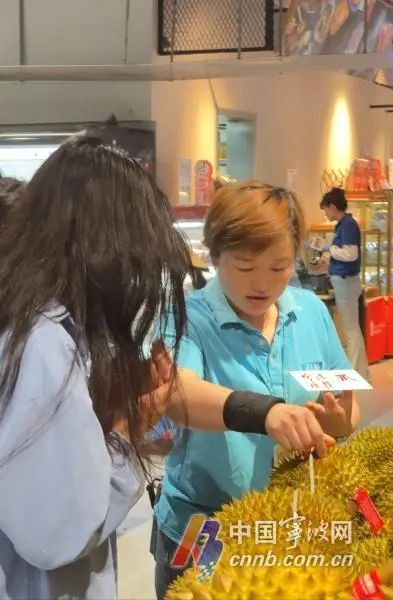 盒马工作人员为顾客挑选榴莲。