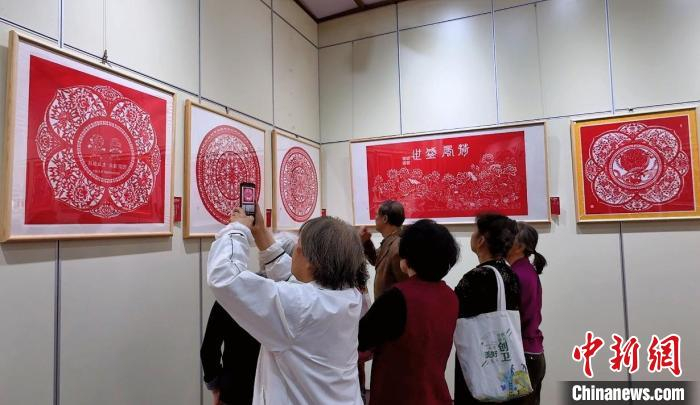  游客在剪纸作品前欣赏、拍照。杨静摄