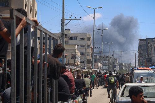 5月7日，以色列在加沙地带南部的拉法发动空袭，巴勒斯坦人聚集在街道上，烟雾滚滚。（图片来源：视觉中国）