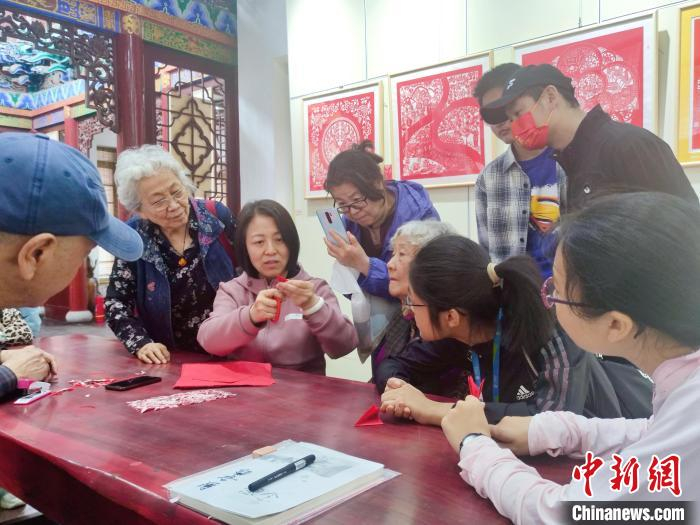  传承人梁盛萍现场传授剪纸技艺。梁盛萍供图