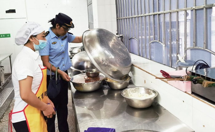 市场监管执法人员对学校食堂储存食品进行安全与卫生检查。
