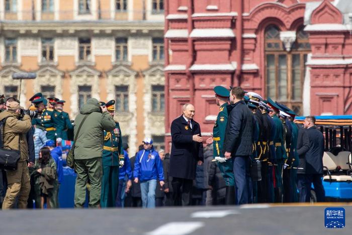   5月9日，在俄罗斯首都莫斯科，俄罗斯总统普京（中）与参与阅兵式的人员握手。新华社记者 曹阳 摄