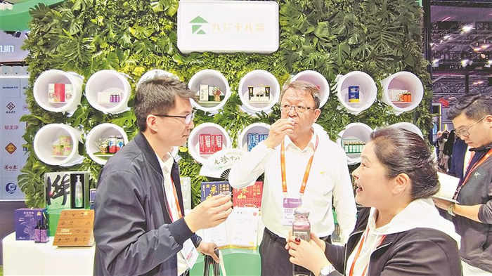     参展客商品尝产品洽谈业务。