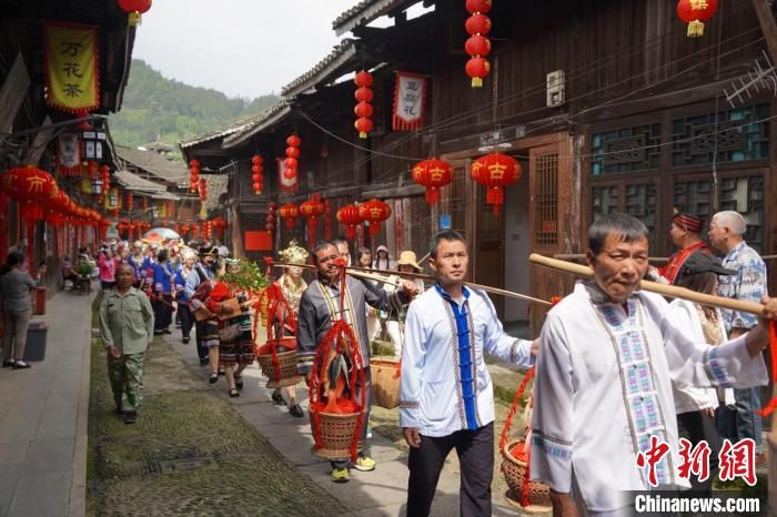 寨市古镇用“抬故事”方式讲述着杨金花乌米饭救兄的故事。唐芳艳摄