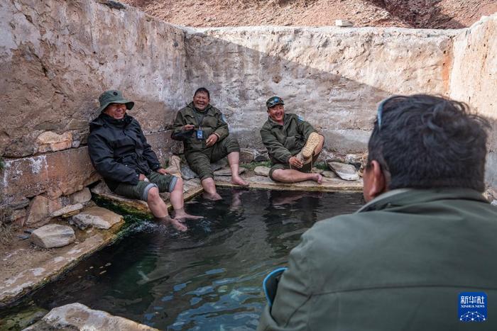 野生动物专业管护队员们在一处废弃的温泉池中泡脚休息（5月8日摄）。新华社记者 丁增尼达 摄