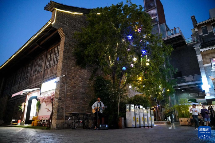 　　一名表演者在钱王街上弹吉他（4月25日摄）。