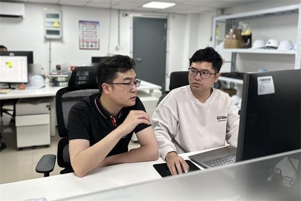 图说：杨钊和同事讨论技术难点。