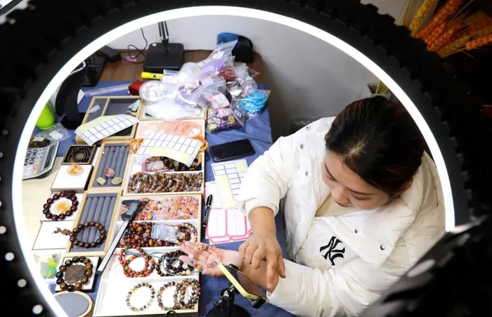 江苏省连云港市，在东海县一水晶电商中心内，工作人员在通过手机进行直播卖货/图源：视觉中国