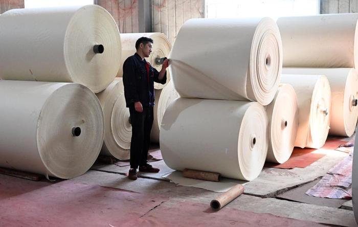   5月14日，在位于丁家桥镇的安徽省泾县三星纸业有限公司，工作人员查看机器加工的书画纸。新华社记者 周牧 摄